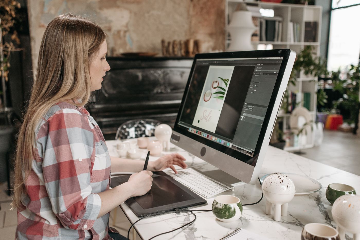A designer creating a product advertisement on a desktop computer and drawing tablet.